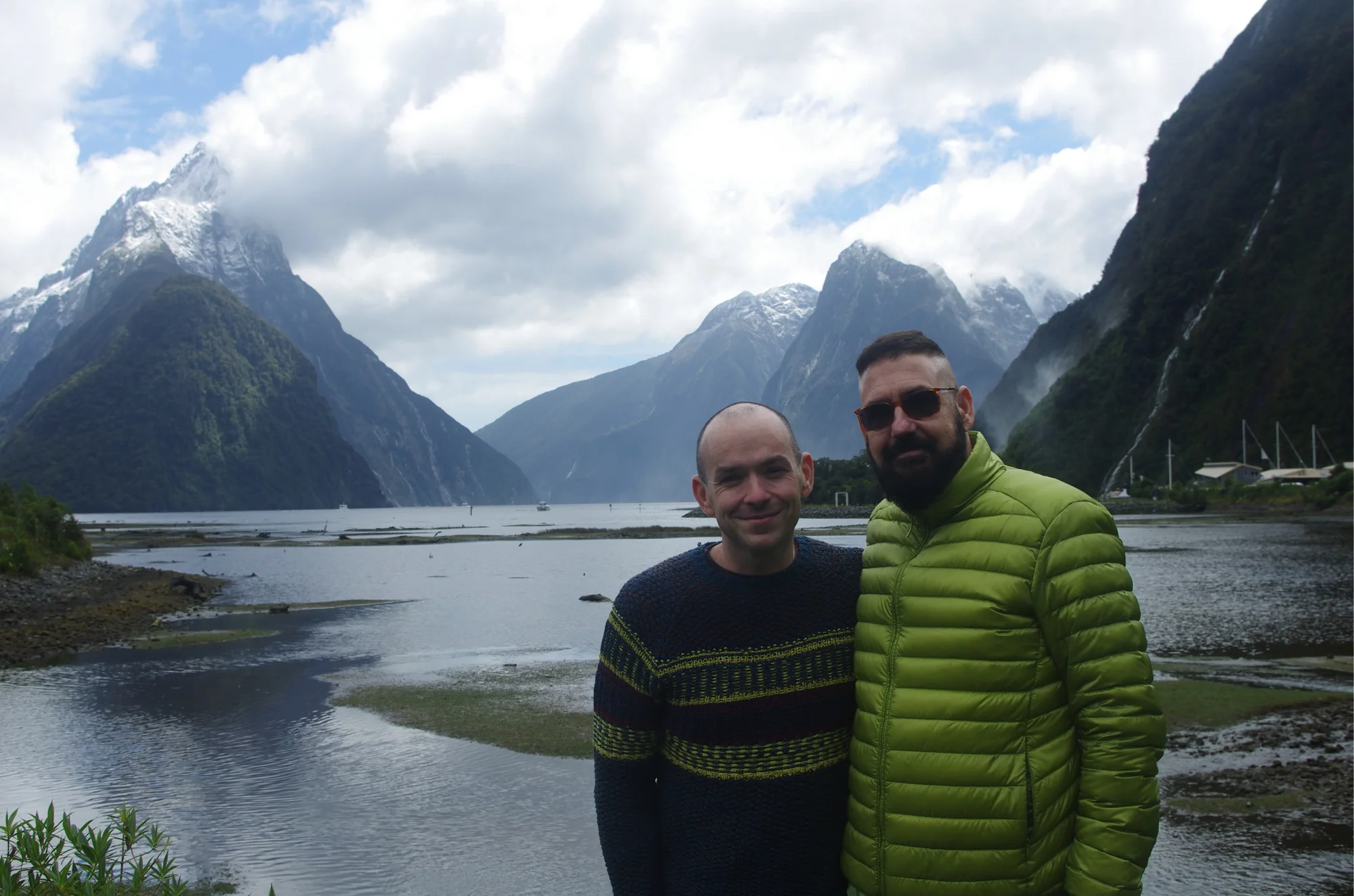The two of us beside the water, with mountains rising into the clouds behind us.